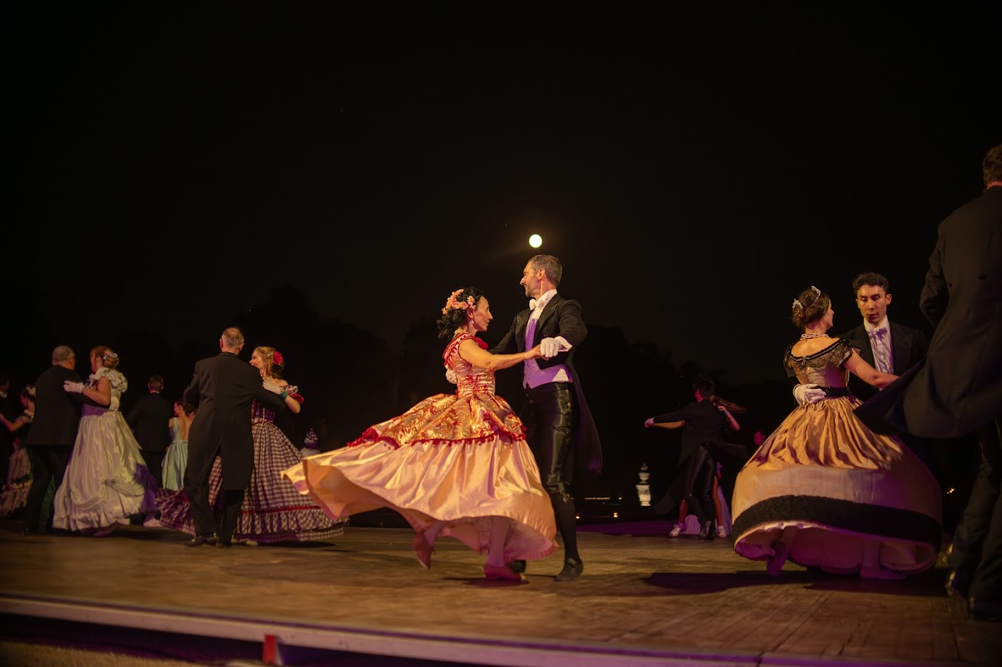 Les danseuses et danseurs de Carnet de Bals valsant lors d'un bal nocturne
