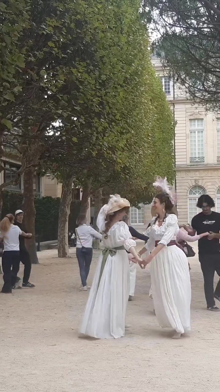 Danseuses en costumes baroques et visiteurs se tenant par la main pendant une initiation dans les jardins