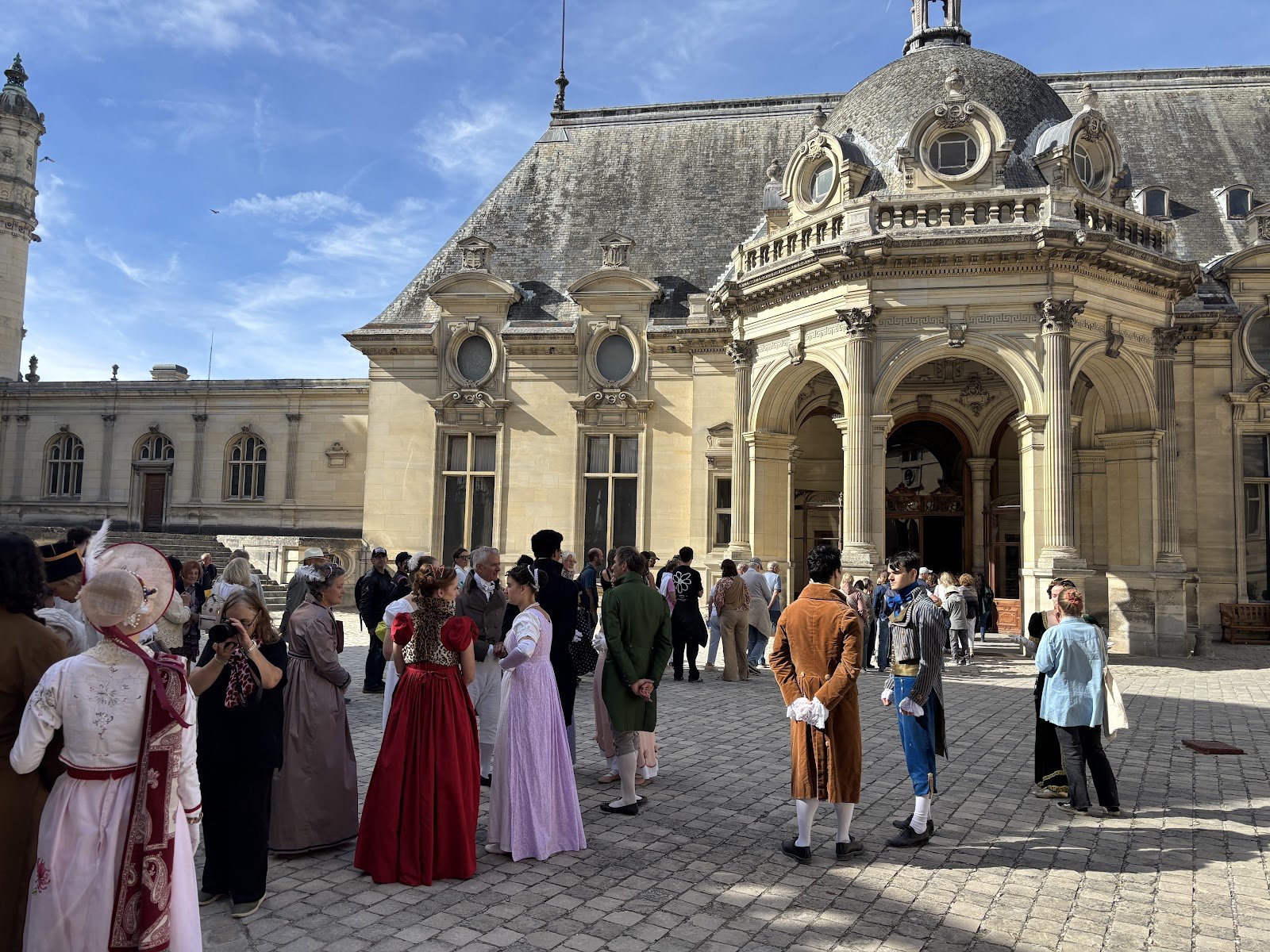 Participants en costumes Premier Empire rassemblés dans la cour du château de Chantilly