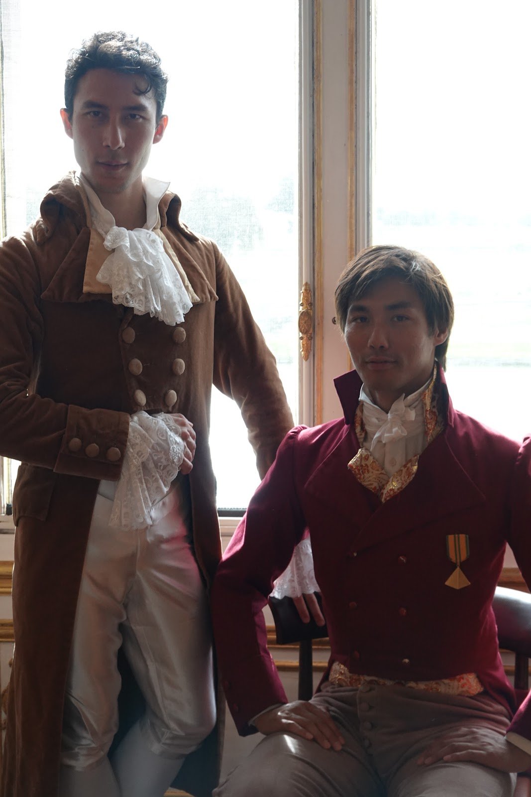 Deux participants en habits Premier Empire posant près d’une fenêtre du château