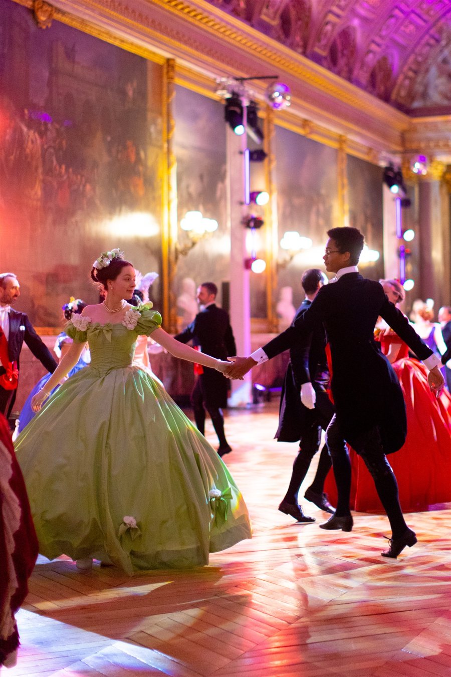 Un couple en costume de bal danse dans les salons de Versailles